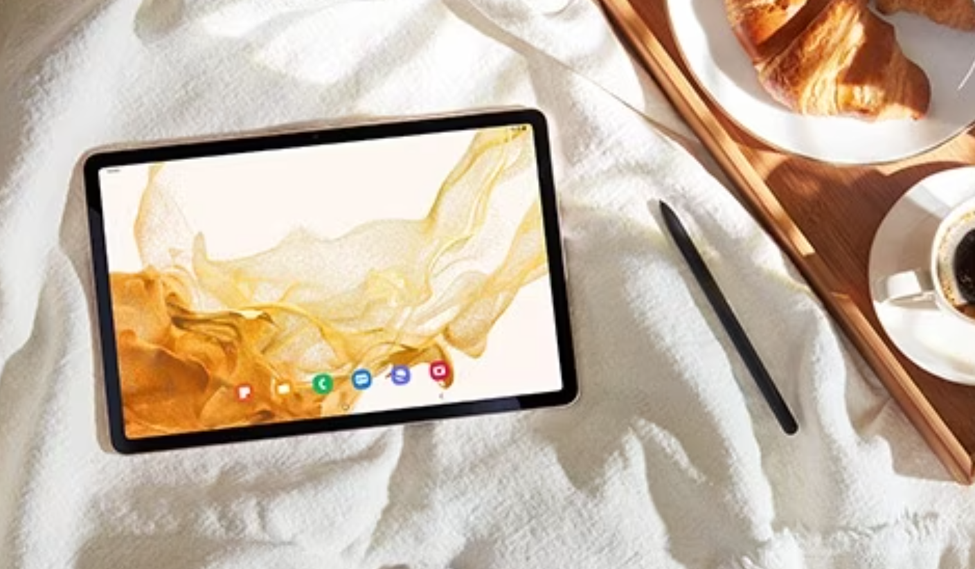 tablette sur des draps avec café et croissant